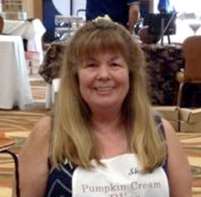 A woman wearing an apron and smiling for the camera.